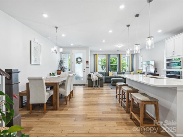 dining area with recessed lighting, light wood-style flooring, and a notable chandelier