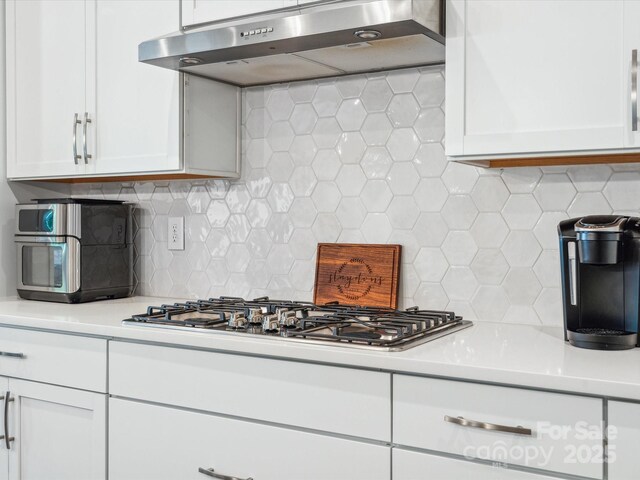 kitchen with light countertops, ventilation hood, stainless steel gas cooktop, and white cabinets