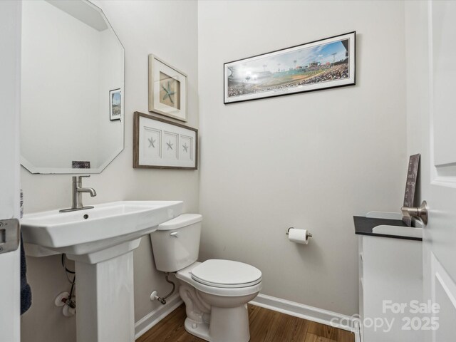 bathroom with toilet, baseboards, and wood finished floors