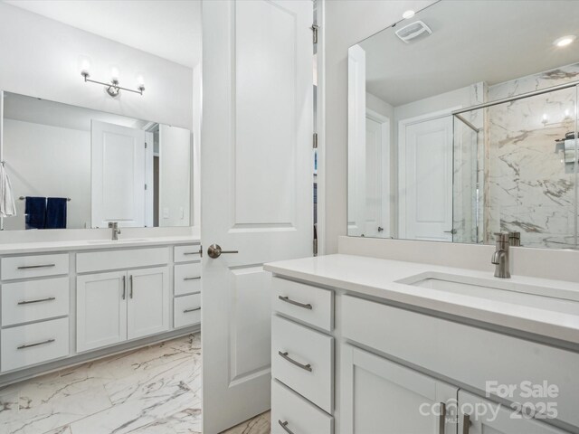 full bathroom featuring a sink, a marble finish shower, two vanities, and marble finish floor