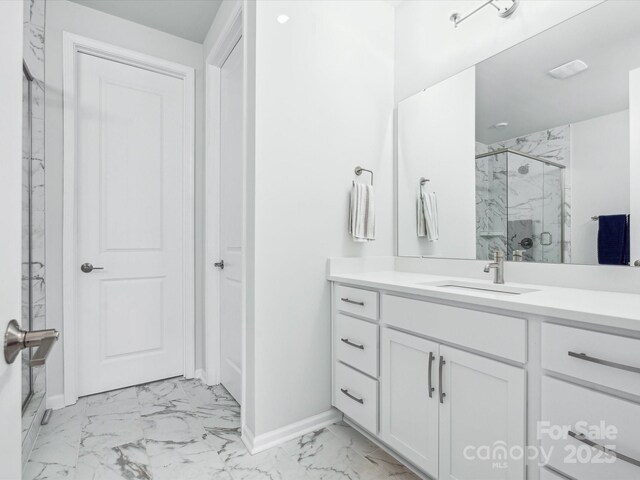 bathroom featuring baseboards, marble finish floor, a marble finish shower, and vanity