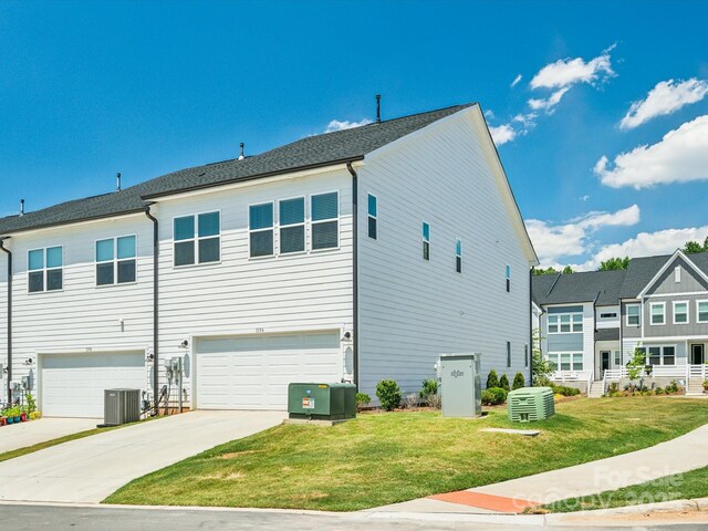 view of side of property featuring a garage, central air condition unit, a lawn, and driveway