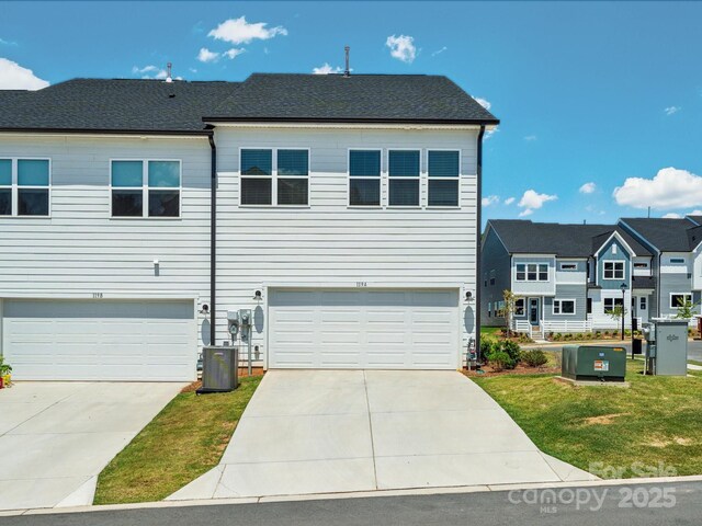 view of property with concrete driveway, cooling unit, a front lawn, and a garage