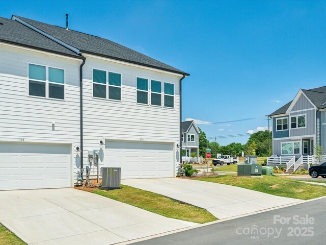 view of home's exterior featuring a garage, central air condition unit, driveway, and a shingled roof
