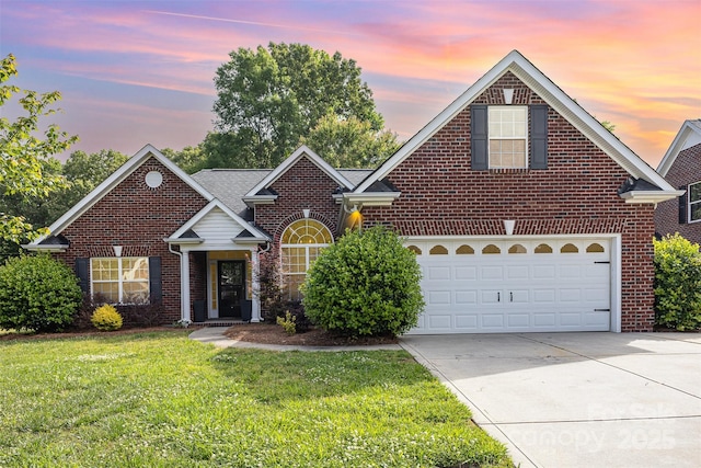 traditional-style home with brick siding, concrete driveway, a yard, and a garage