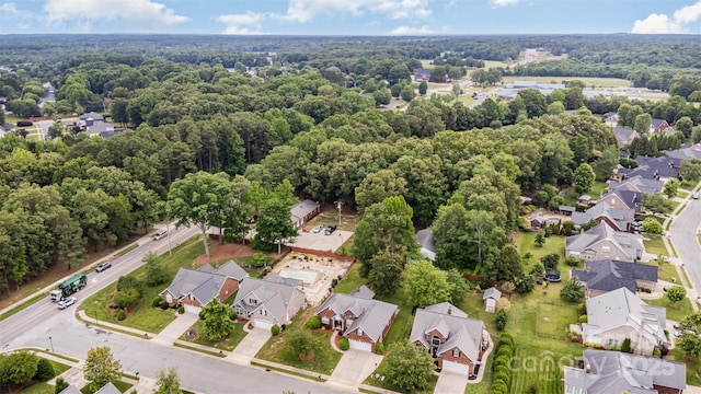aerial view of property and surrounding area featuring nearby suburban area and a heavily wooded area
