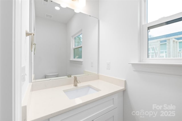 bathroom featuring vanity, visible vents, and toilet