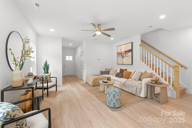 living room featuring a ceiling fan, baseboards, wood finished floors, and stairway
