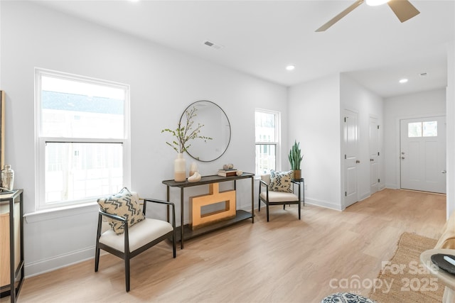 sitting room with baseboards, visible vents, a wealth of natural light, and light wood finished floors