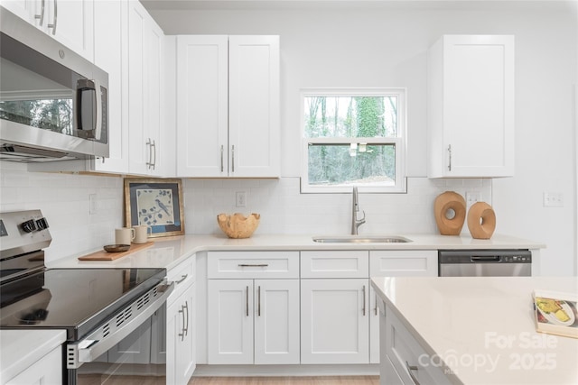 kitchen featuring white cabinets, stainless steel appliances, a sink, and light countertops