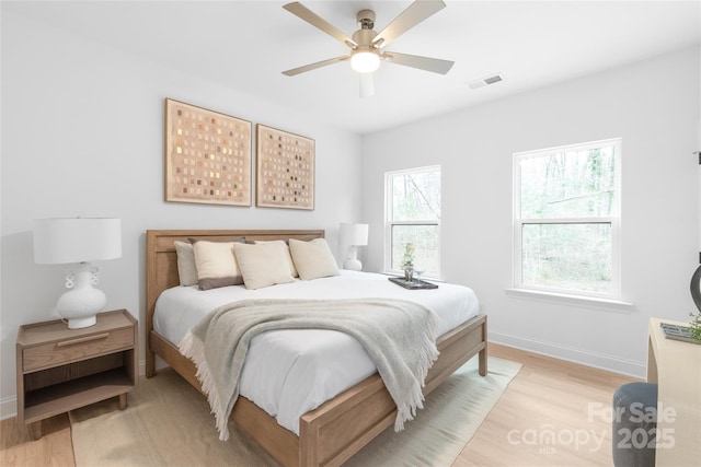 bedroom with visible vents, light wood-style flooring, ceiling fan, and baseboards