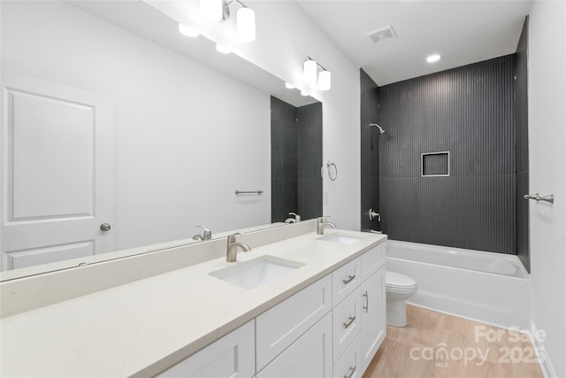 full bathroom featuring toilet, visible vents, a sink, and wood finished floors