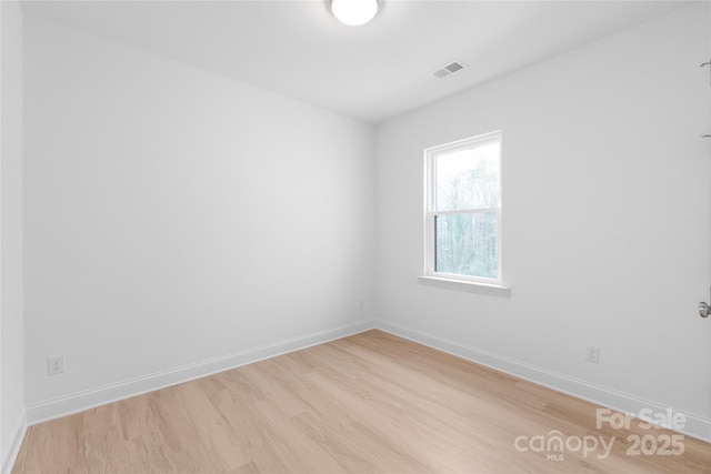 unfurnished room featuring baseboards, visible vents, and light wood finished floors