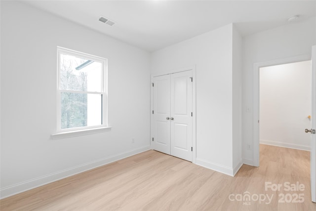 empty room with baseboards, plenty of natural light, light wood-style flooring, and visible vents