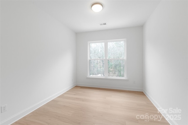 empty room featuring baseboards, visible vents, and light wood finished floors