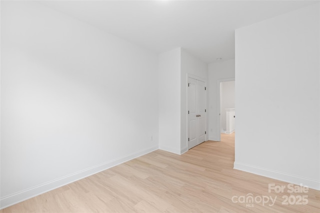 empty room featuring baseboards and light wood finished floors