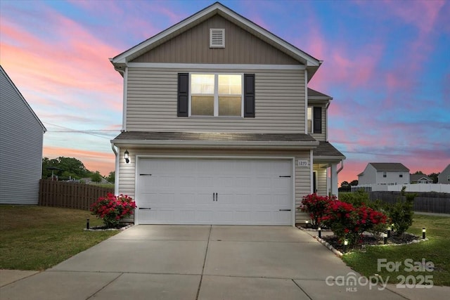 traditional-style home with a garage, fence, a yard, and concrete driveway