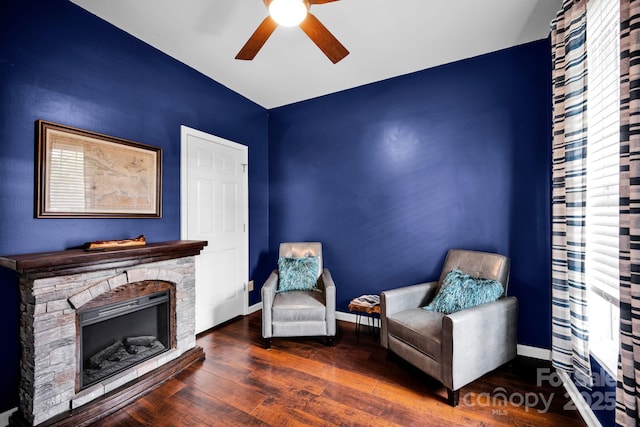 sitting room with a ceiling fan, wood finished floors, baseboards, and a fireplace