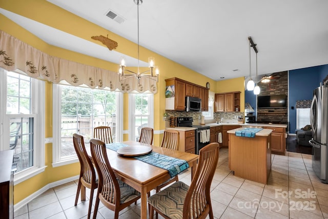 dining area with plenty of natural light, a chandelier, light tile patterned floors, and baseboards