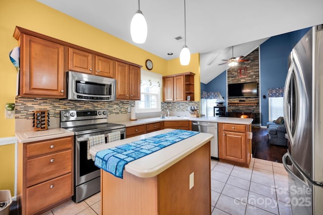 kitchen featuring appliances with stainless steel finishes, a peninsula, vaulted ceiling, open floor plan, and decorative backsplash