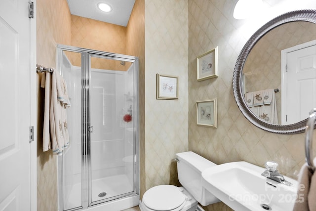 bathroom with a sink, a stall shower, and toilet