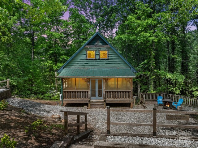 rear view of house featuring french doors, a fire pit, covered porch, and metal roof