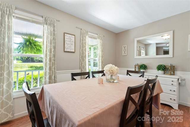 dining space with wainscoting and wood finished floors