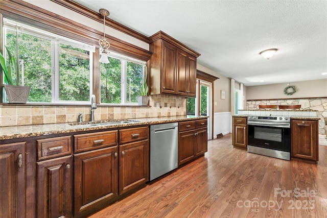 kitchen featuring plenty of natural light, a sink, light wood-style floors, and appliances with stainless steel finishes