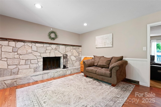 living room featuring wainscoting, wood finished floors, and a fireplace