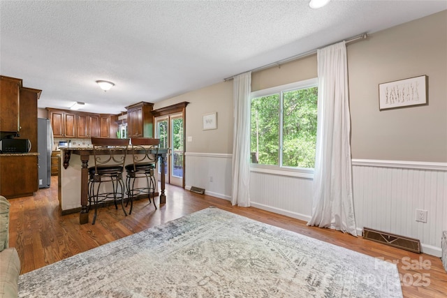kitchen with freestanding refrigerator, a textured ceiling, visible vents, and a breakfast bar