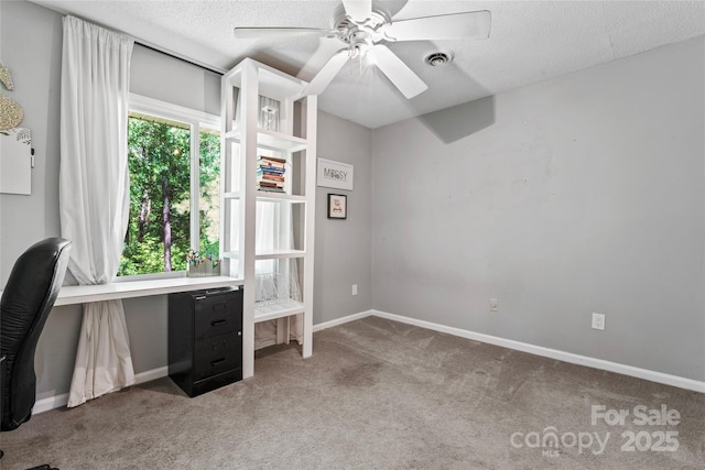 unfurnished office with a ceiling fan, a textured ceiling, visible vents, baseboards, and carpet flooring