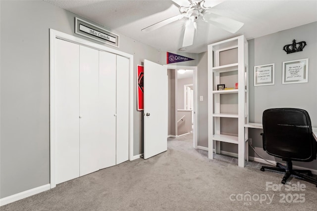 carpeted office space with baseboards and ceiling fan
