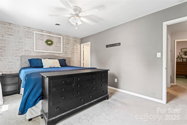 bedroom featuring baseboards, an accent wall, visible vents, and light carpet