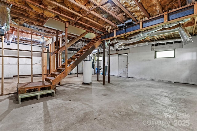 below grade area featuring concrete block wall, stairway, and gas water heater