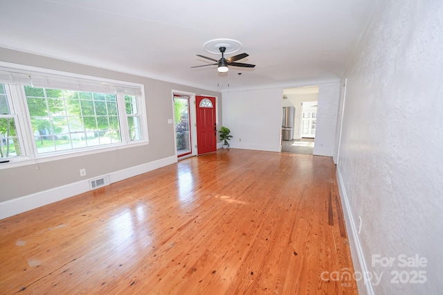 unfurnished living room with baseboards, ceiling fan, light wood-type flooring, and visible vents