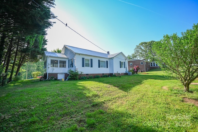 back of house featuring a yard, crawl space, and metal roof