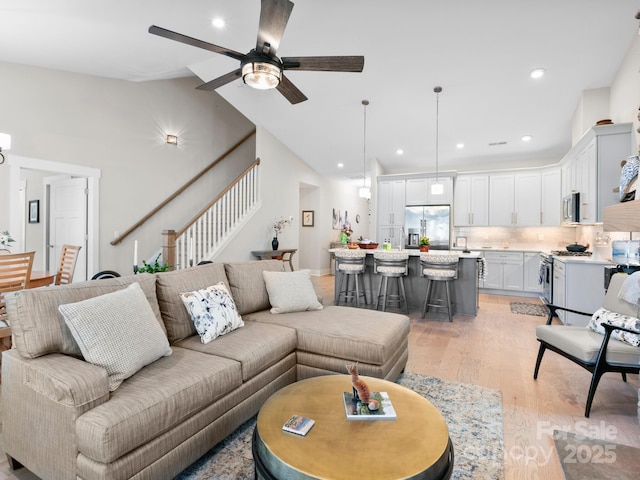 living area featuring light wood-style flooring, stairway, ceiling fan, recessed lighting, and high vaulted ceiling