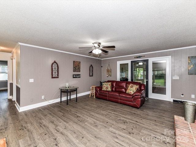 living area with ornamental molding, a ceiling fan, wood finished floors, a textured ceiling, and baseboards