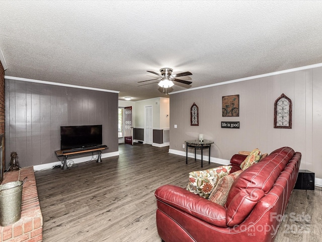 living area featuring wood finished floors, ceiling fan, crown molding, a textured ceiling, and wooden walls