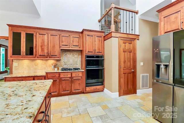 4509 Rosecliff Dr, Charlotte, NC 28277 - kitchen featuring stainless steel refrigerator with ice dispenser, crown molding, decorative backsplash, light stone counters, and glass insert cabinets