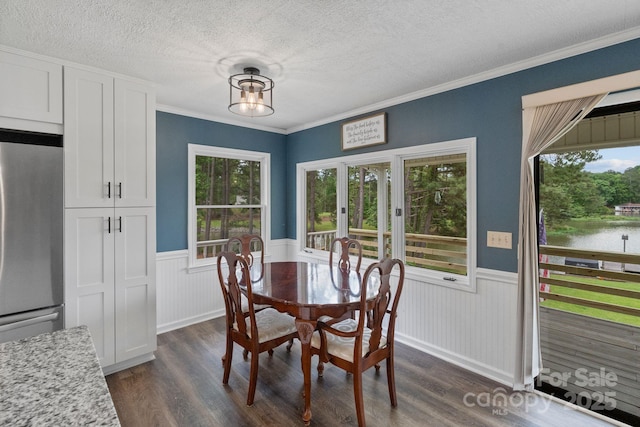 dining space featuring a wainscoted wall, dark wood-type flooring, plenty of natural light, a textured ceiling, and crown molding