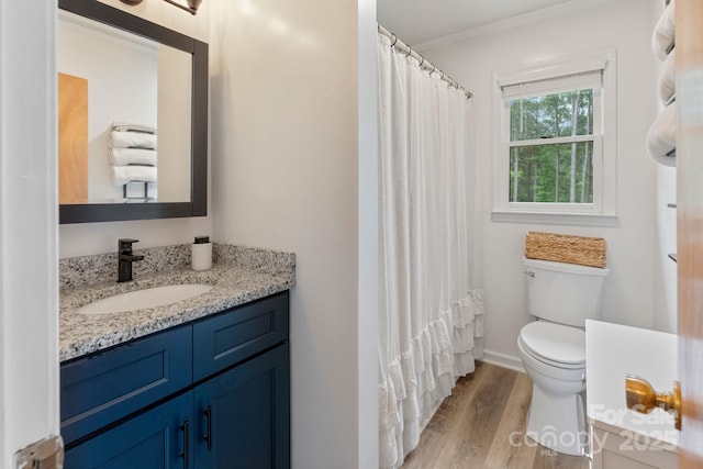 bathroom with wood finished floors, toilet, ornamental molding, vanity, and curtained shower
