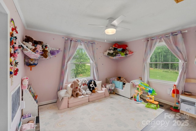 playroom featuring ceiling fan, ornamental molding, and baseboards