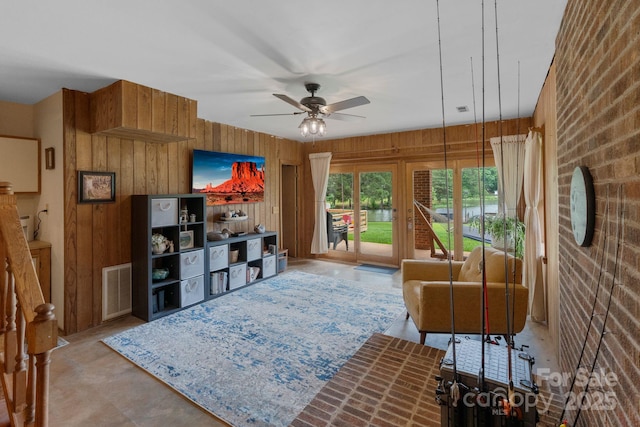 living room featuring a ceiling fan and wood walls