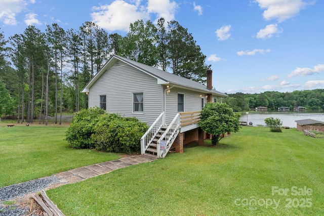view of side of home with a chimney, a water view, a yard, and stairs