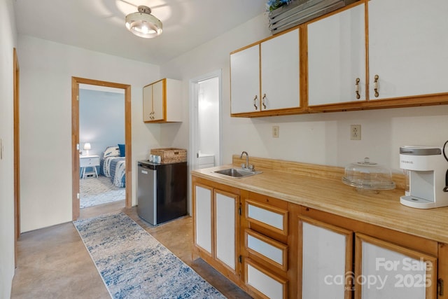 kitchen with freestanding refrigerator, a sink, light countertops, and white cabinets