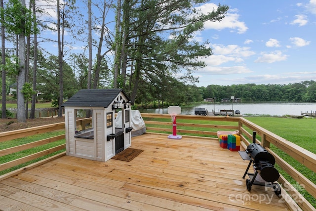 deck featuring a water view, a lawn, and an outbuilding