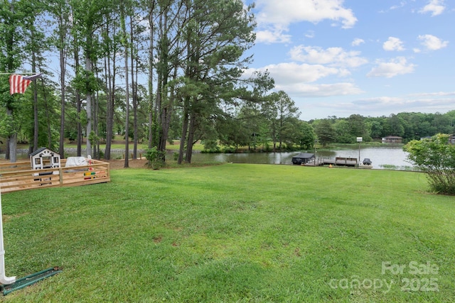 view of green lawn featuring a water view and a dock