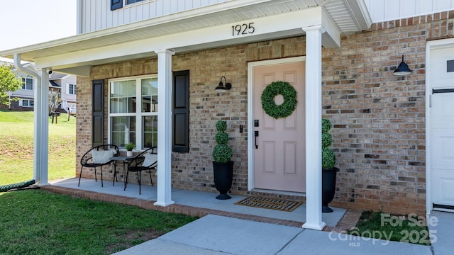 entrance to property with board and batten siding, a porch, and brick siding