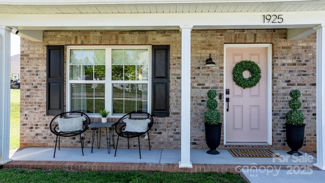 property entrance with a porch and brick siding